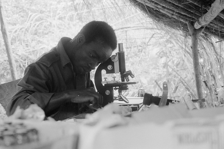 A student uses a microscope during a PAIGC medical consultation in a college in Campada, 1973. Source: Roel Coutinho, Guinea-Bissau and Senegal Photographs (1973–1974)